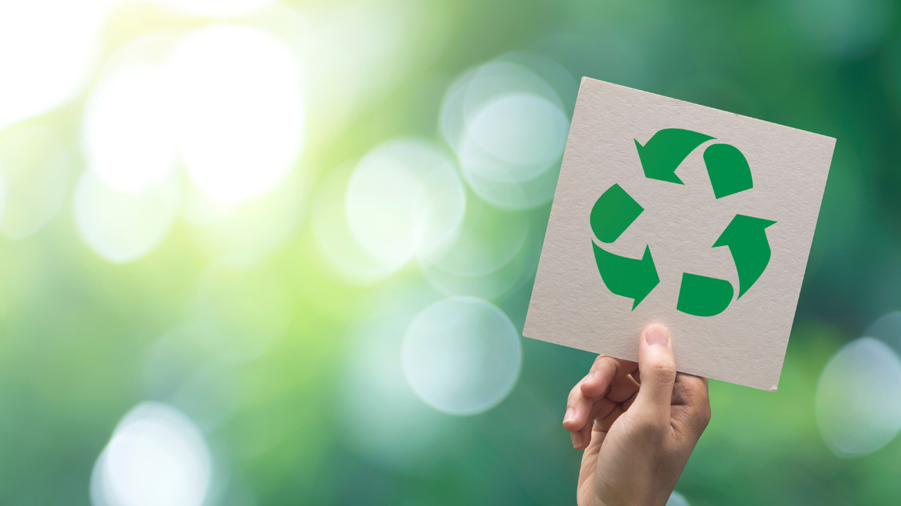 Main tenant une pancarte avec le logo recyclage